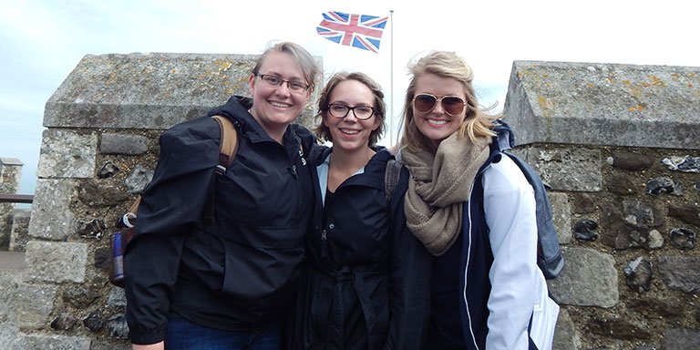 Three girls standing in front of a British Flag.