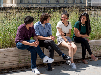 four students sitting on a ledge together
